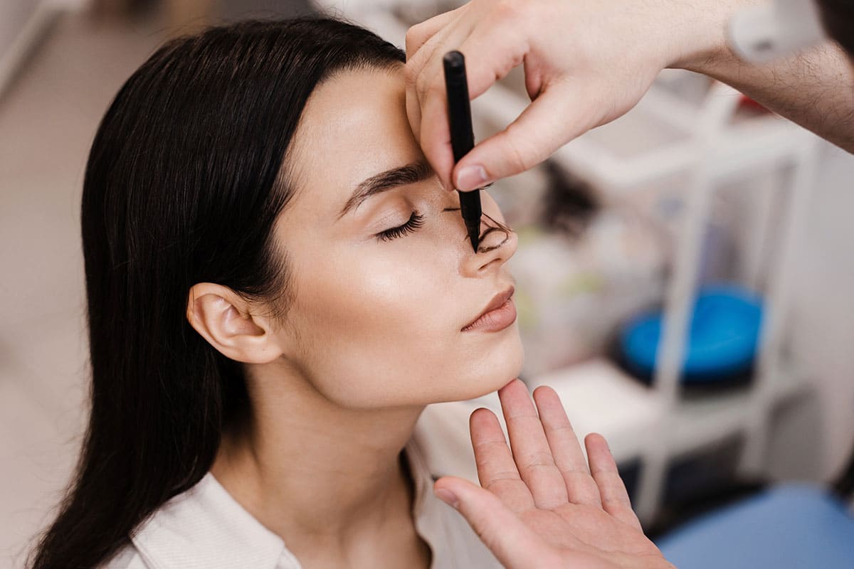 Doctor marking a woman's nose to determine the rhinoplasty technique: open or closed.