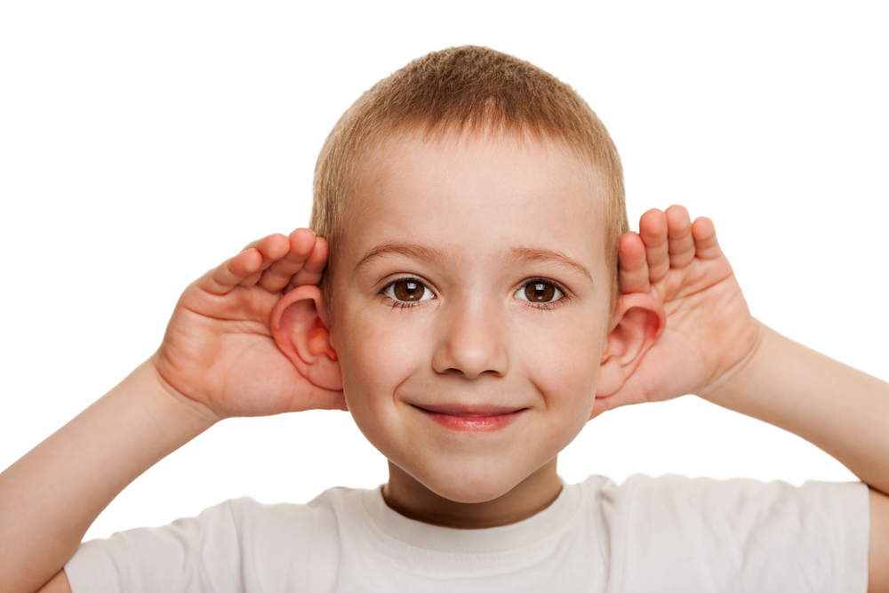 Young boy holding his ears, symbolizing consideration for otoplasty surgery.