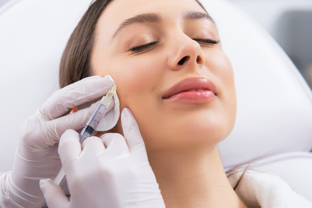 Close-up of a relaxed woman receiving a Botox injection in her cheek.