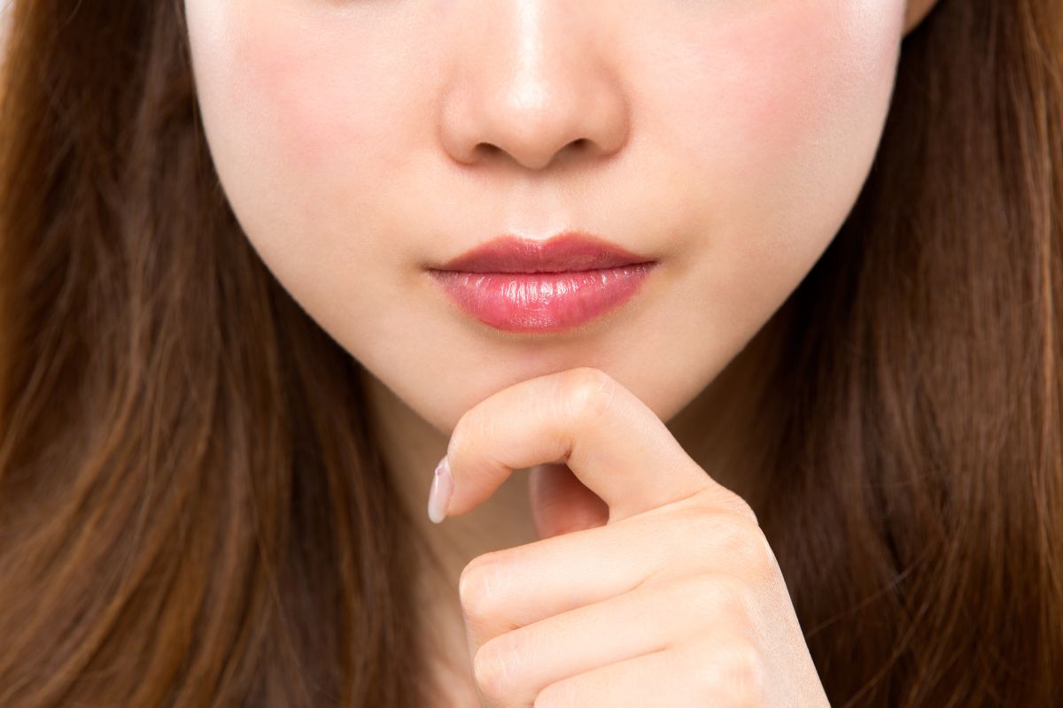 Close-up of a contemplative woman's lower face, considering Kybella for chin fat.