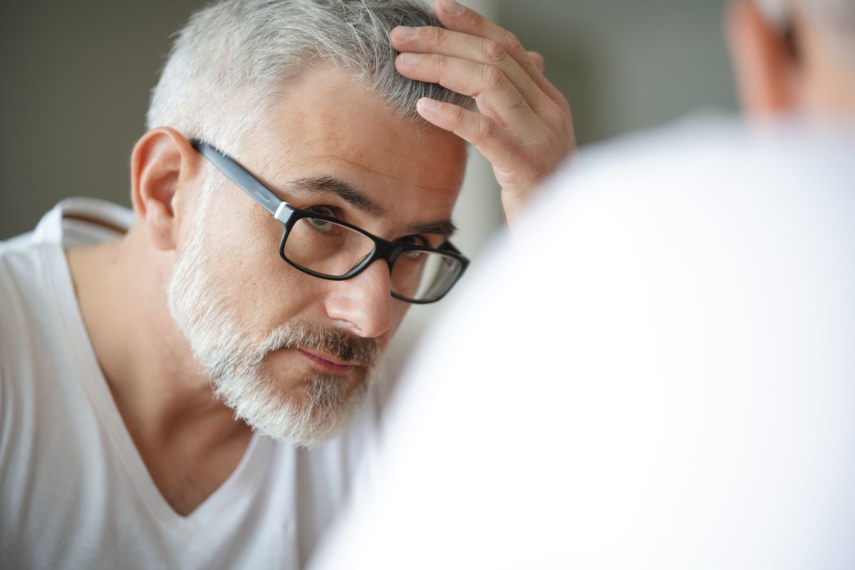 Close-up of a man assessing his hairline, considering FUE hair restoration surgery.