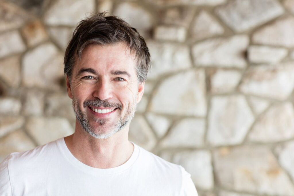 Smiling man with grey hair indicating successful PRP hair restoration therapy.