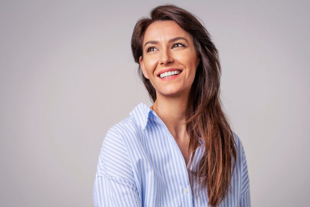 Smiling woman with healthy hair representing the success of stem cell hair restoration treatment.