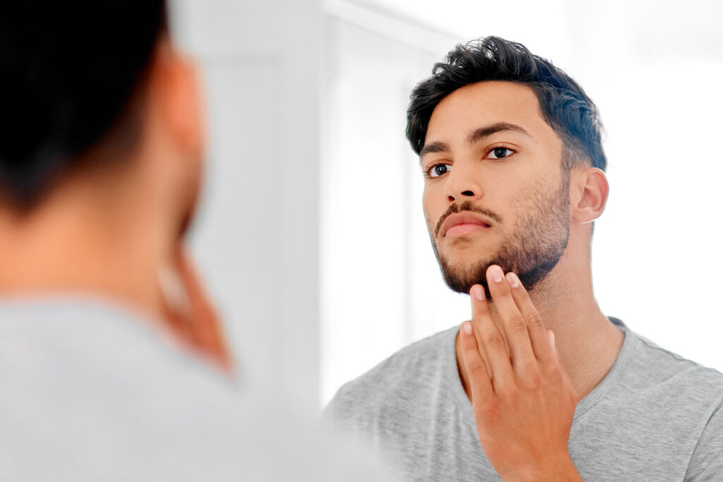 blog-the-best-skincare-routine man looking in the mirror after his beard transplant in Miami, FL