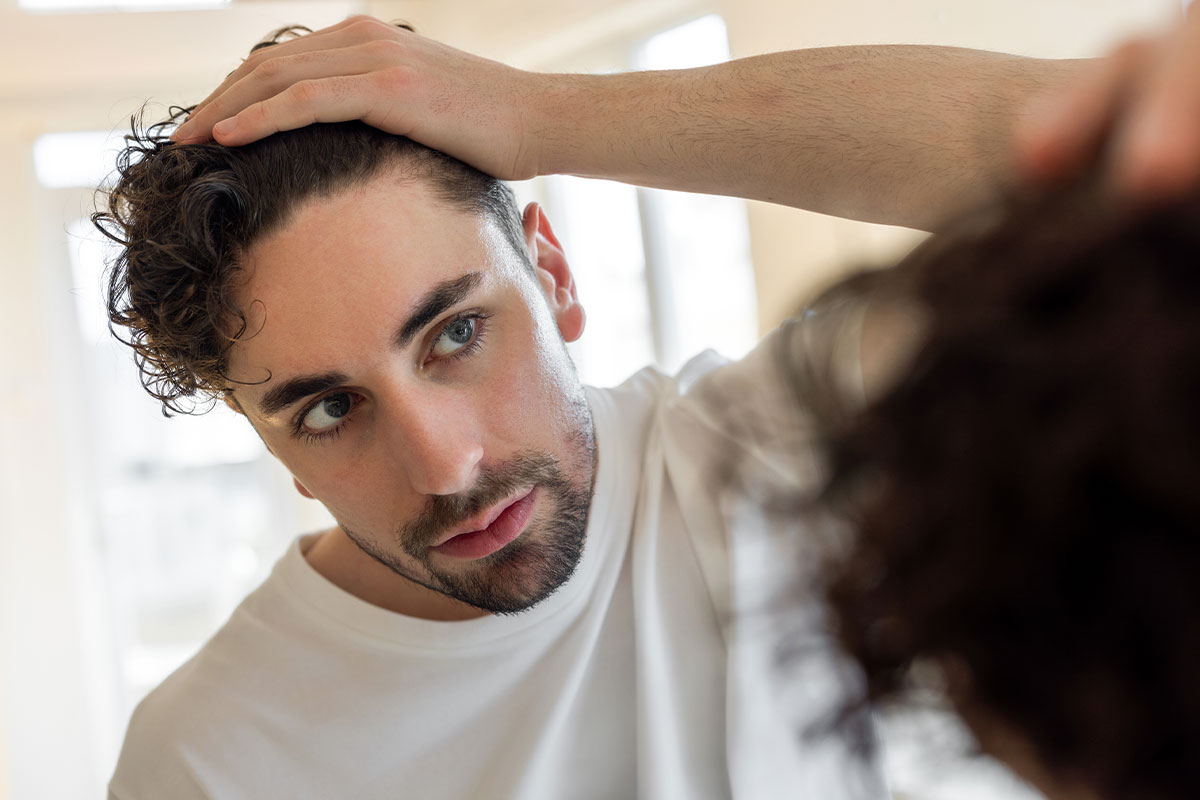 man looking in the mirror after his hair transplant in Miami