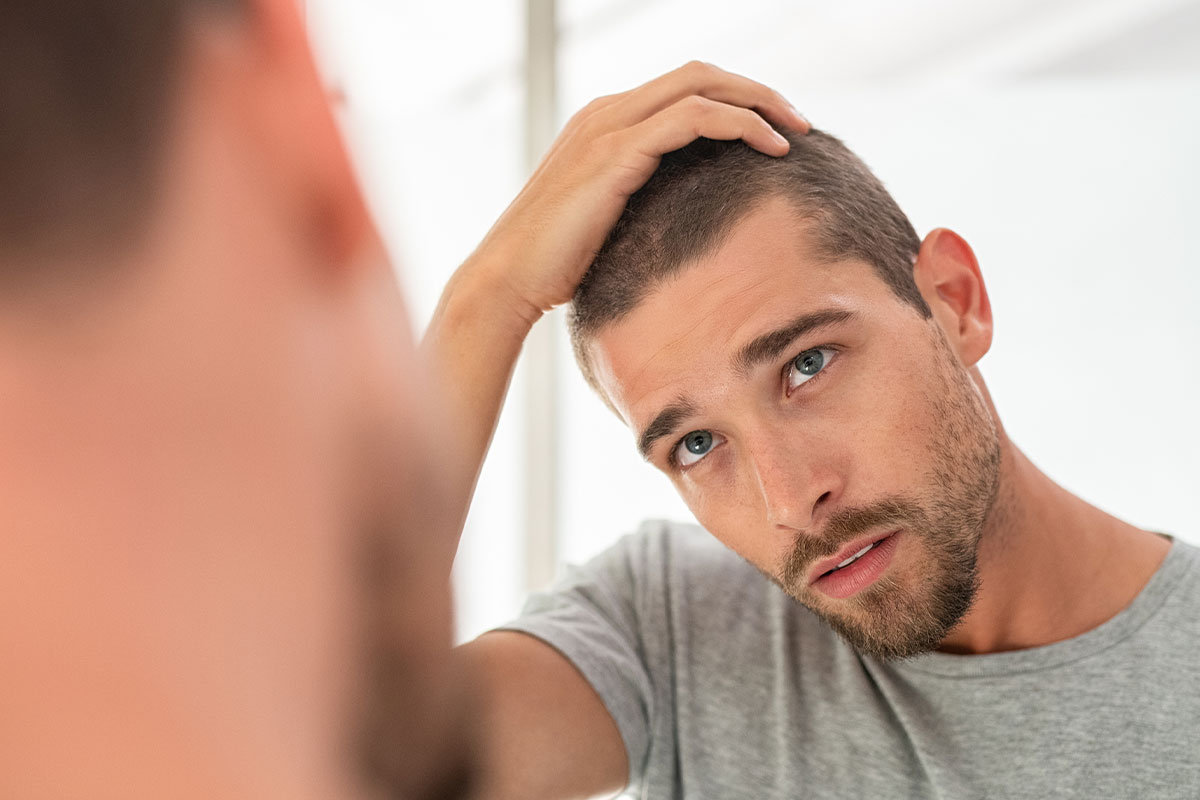 man looking in the mirror after getting hair restoration in Miami, FL