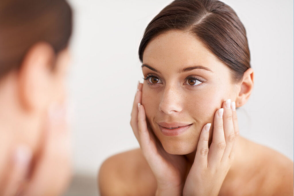 woman looking in the mirror after her rhinoplasty in Miami, FL